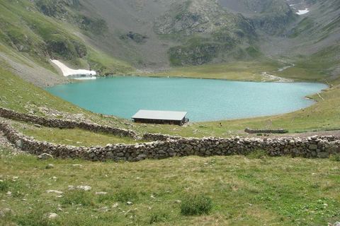 Le lac de la Muzelle et son refuge, en août, sous les pentes herbeuses