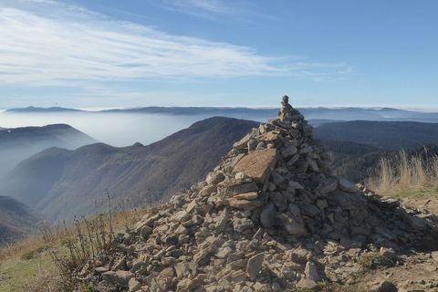 Le cairn du Crêt de Chalam avec la vue sur les crêts en automne