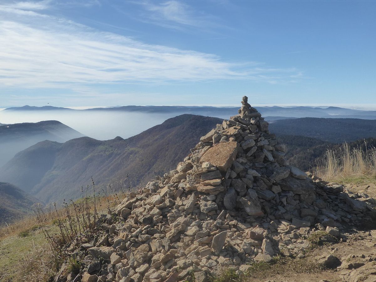 Le cairn du Crêt de Chalam avec la vue sur les crêts en automne