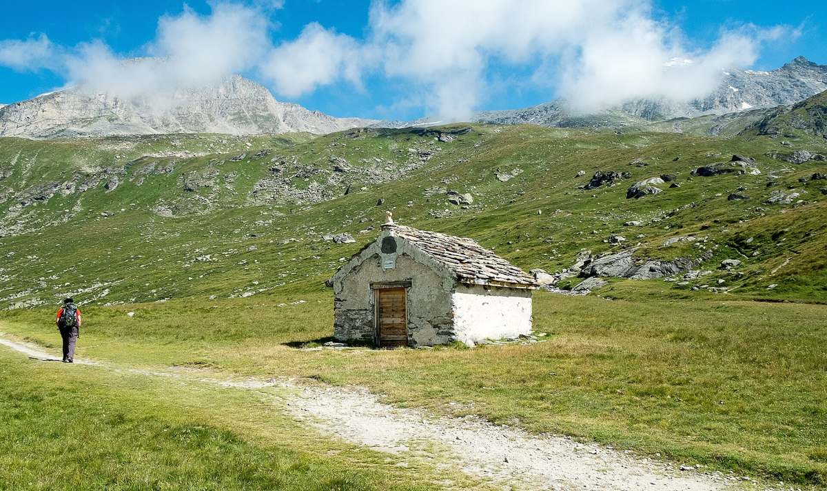 La chapelle du Fond d'Aussois sur le plateau d'alpage, avec un randonneur sur le sentier